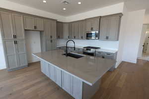 Kitchen with appliances with stainless steel finishes, a sink, visible vents, and light wood-type flooring