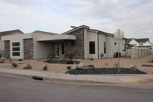 View of front of home with central air condition unit, stone siding, and stucco siding