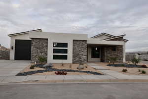 Modern home with stucco siding, concrete driveway, and stone siding