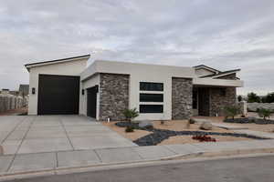 Modern home with a garage, stucco siding, and stone siding