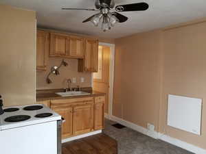 Kitchen with dark wood-style flooring, electric range, dark countertops, ceiling fan, and a sink