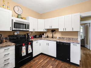 Kitchen featuring a sink, white cabinets, black appliances, and dark wood-style floors