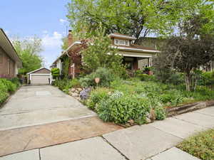 Bungalow-style house featuring brick siding, an outbuilding, a chimney, and a detached garage