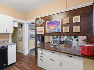 Kitchen featuring butcher block countertops, baseboards, black dishwasher, white cabinets, and dark wood finished floors