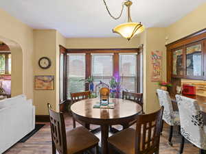 Dining area with arched walkways and wood finished floors