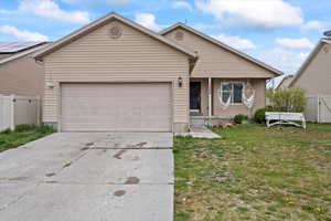 Single story home with an attached garage, a front lawn, fence, and concrete driveway