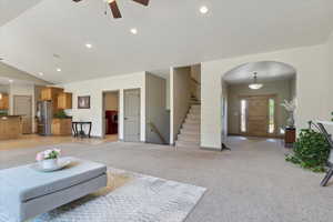 Living room with stairs, ceiling fan, light colored carpet, recessed lighting, and arched walkways