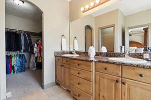 Bathroom featuring double vanity, a sink, a walk in closet, and tile patterned floors