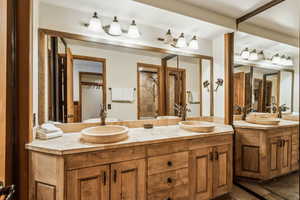Full bathroom with double vanity, tiled shower, and a sink
