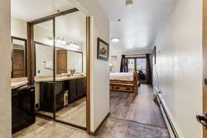 Ensuite bathroom featuring baseboard heating, baseboards, connected bathroom, and vanity