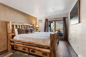 Bedroom featuring wood finished floors, access to outside, a textured wall, and a wall mounted AC