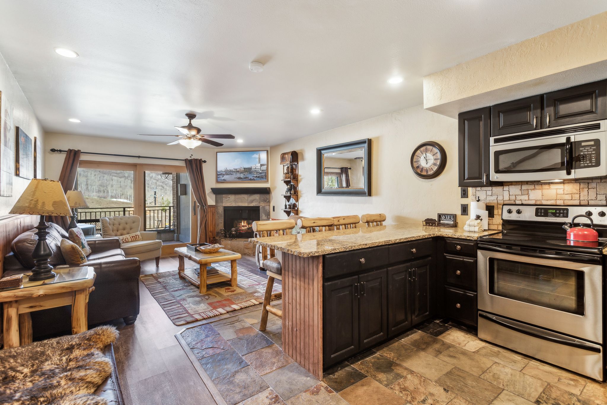 Kitchen with light stone counters, appliances with stainless steel finishes, ceiling fan, a peninsula, and a kitchen breakfast bar