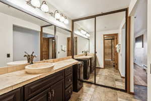 Full bathroom featuring stone tile floors, a shower stall, a sink, a baseboard radiator, and wine cooler