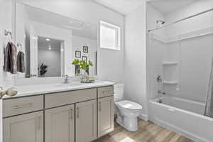 Bathroom with toilet, shower / washtub combination, wood finished floors, and vanity