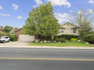View of front facade featuring an attached garage, a front yard, brick siding, and concrete driveway
