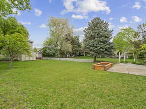 View of yard with a garden, an outbuilding, a patio area, fence, and a storage unit