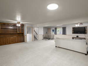 Living area featuring stairway, a wainscoted wall, and ceiling fan