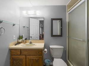 Full bathroom featuring an enclosed shower, vanity, and toilet