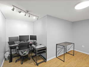 Office featuring baseboards, rail lighting, crown molding, and wood finished floors