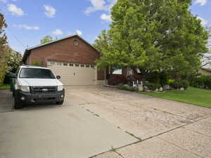 View of front of property featuring concrete driveway, brick siding, an attached garage, and a front yard