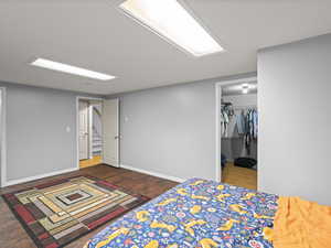 Bedroom featuring baseboards, a walk in closet, wood finished floors, and a closet