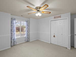 Unfurnished bedroom with visible vents, a textured ceiling, carpet, and baseboards