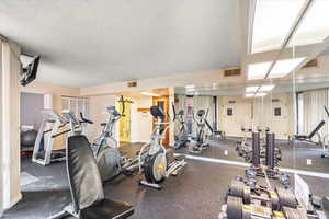 Workout area featuring visible vents, a textured ceiling, and baseboards