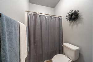 Full bath featuring toilet and curtained shower