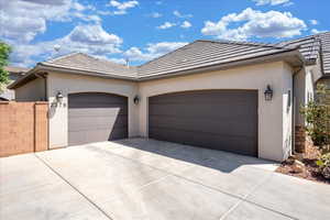 Single story home featuring an attached garage, driveway, a tile roof, and stucco siding