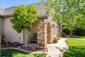 View of side of property featuring a lawn, stucco siding, a tile roof, and stone siding