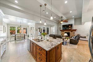 Kitchen with a ceiling fan, appliances with stainless steel finishes, brown cabinets, a sink, and light tile patterned flooring