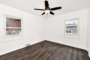 Spare room with baseboards, a ceiling fan, dark wood-type flooring, and visible vents