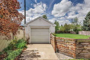 Detached garage featuring fence and concrete driveway