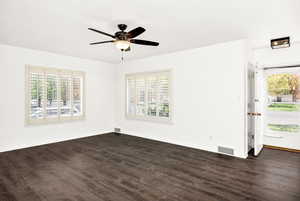 Empty room with baseboards, ceiling fan, dark wood finished floors, and visible vents