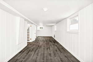 Below grade area featuring dark wood finished floors, a decorative wall, and stairway