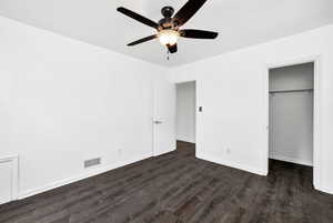 Unfurnished bedroom with visible vents, a closet, dark wood-style flooring, baseboards, and a spacious closet