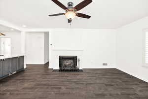 Unfurnished living room with a ceiling fan, a fireplace, baseboards, dark wood-style floors, and recessed lighting