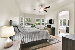 Bedroom with arched walkways, ensuite bath, multiple windows, and light carpet