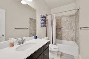 Bathroom with vanity, tile patterned flooring, shower / bath combo, and toilet