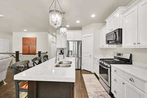Kitchen featuring a sink, dark wood finished floors, a kitchen island with sink, and stainless steel appliances