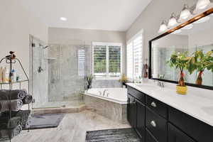 Full bath with a sink, double vanity, a shower stall, and a bath