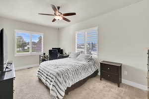 Bedroom featuring baseboards, a ceiling fan, and light carpet