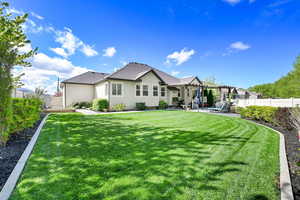 Rear view of property featuring a pergola, a patio, a fenced backyard, stucco siding, and a lawn
