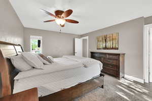 Bedroom with ceiling fan, light carpet, and baseboards