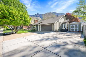 Ranch-style house with a garage, a shed, a mountain view, a chimney, and driveway