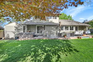 Back of house featuring outdoor lounge area, a hot tub, fence, and a yard