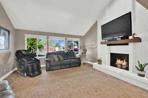 Carpeted living area featuring high vaulted ceiling, baseboards, and a fireplace