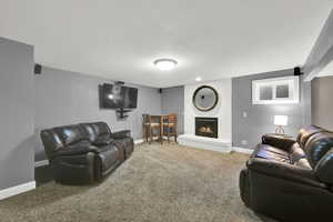 Living room with a fireplace, baseboards, and carpet