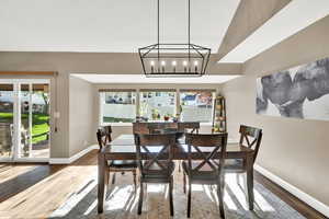 Dining space featuring baseboards, a notable chandelier, a healthy amount of sunlight, and wood finished floors