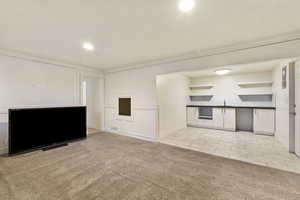 Unfurnished living room featuring light tile patterned floors, light colored carpet, visible vents, recessed lighting, and a sink